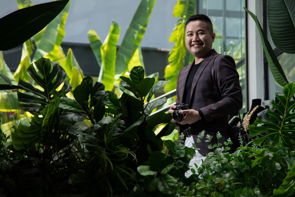 Kevin Lee holding a camera among tropical plants