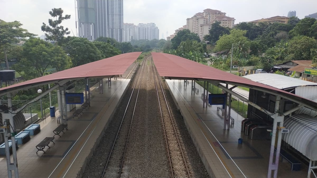 KTM 泗岩沫站：两座红色顶篷的月台夹着铁轨，远处是公寓楼